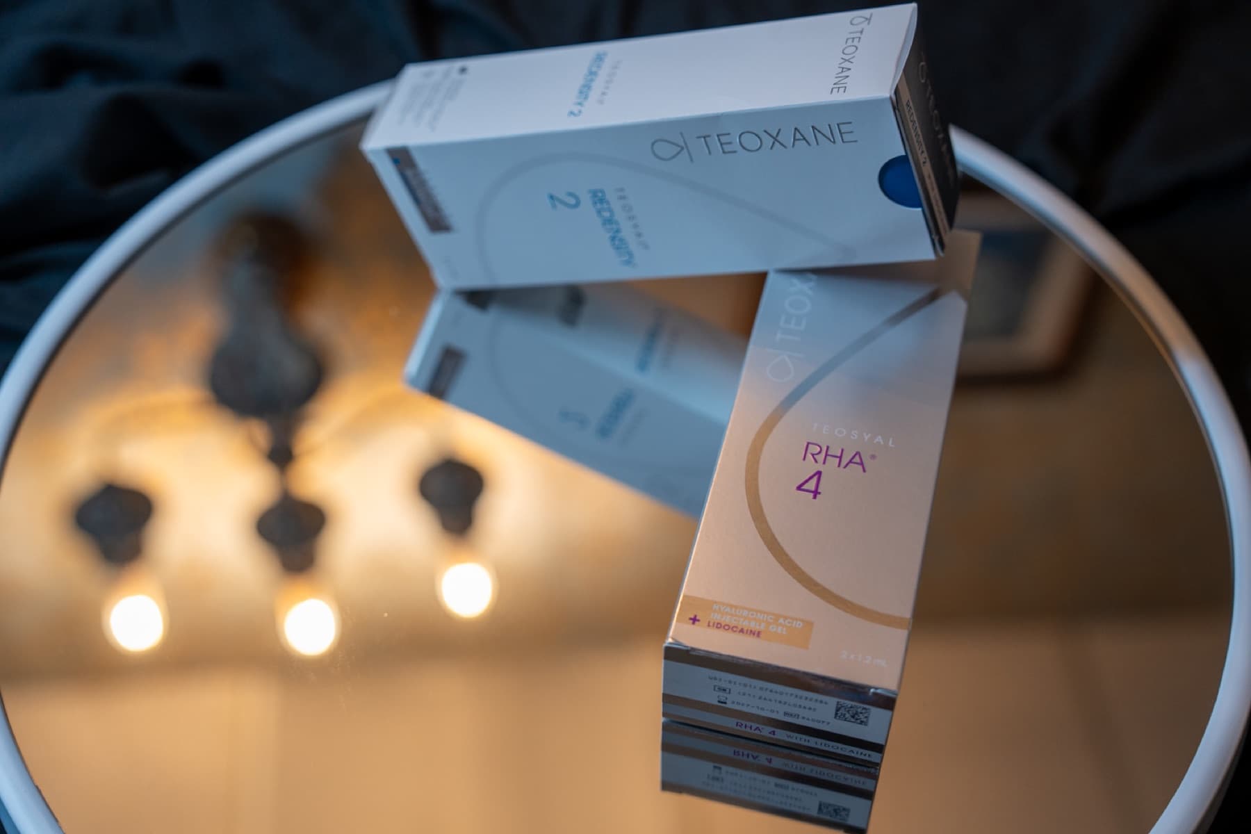 Teoxane RHA 4 and Redensity 2 filler boxes on the mirrored tray under the sconce at LNO Boutique, Centennial