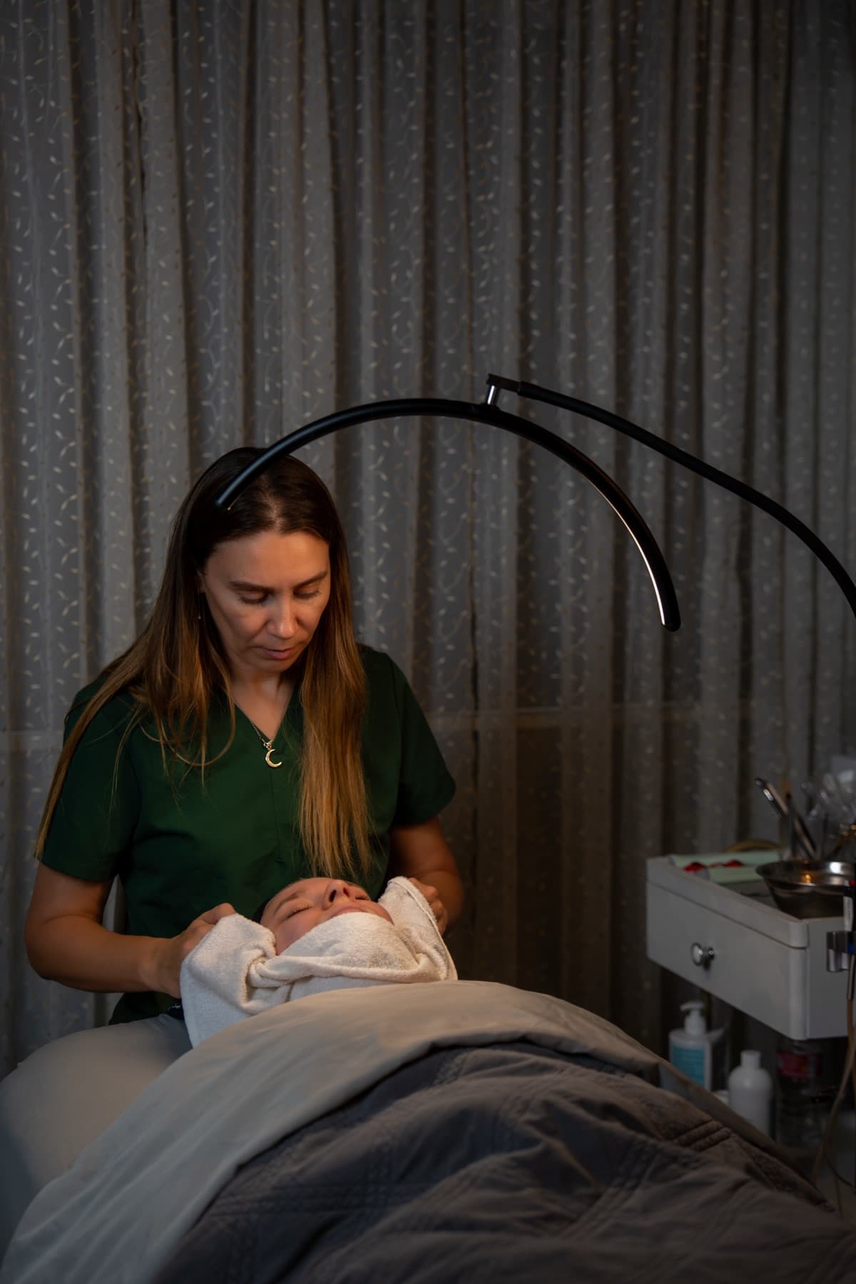 Esthetician removing a warm towel at the end of a HydraFacial in the treatment room at LNO Boutique in Centennial, Denver