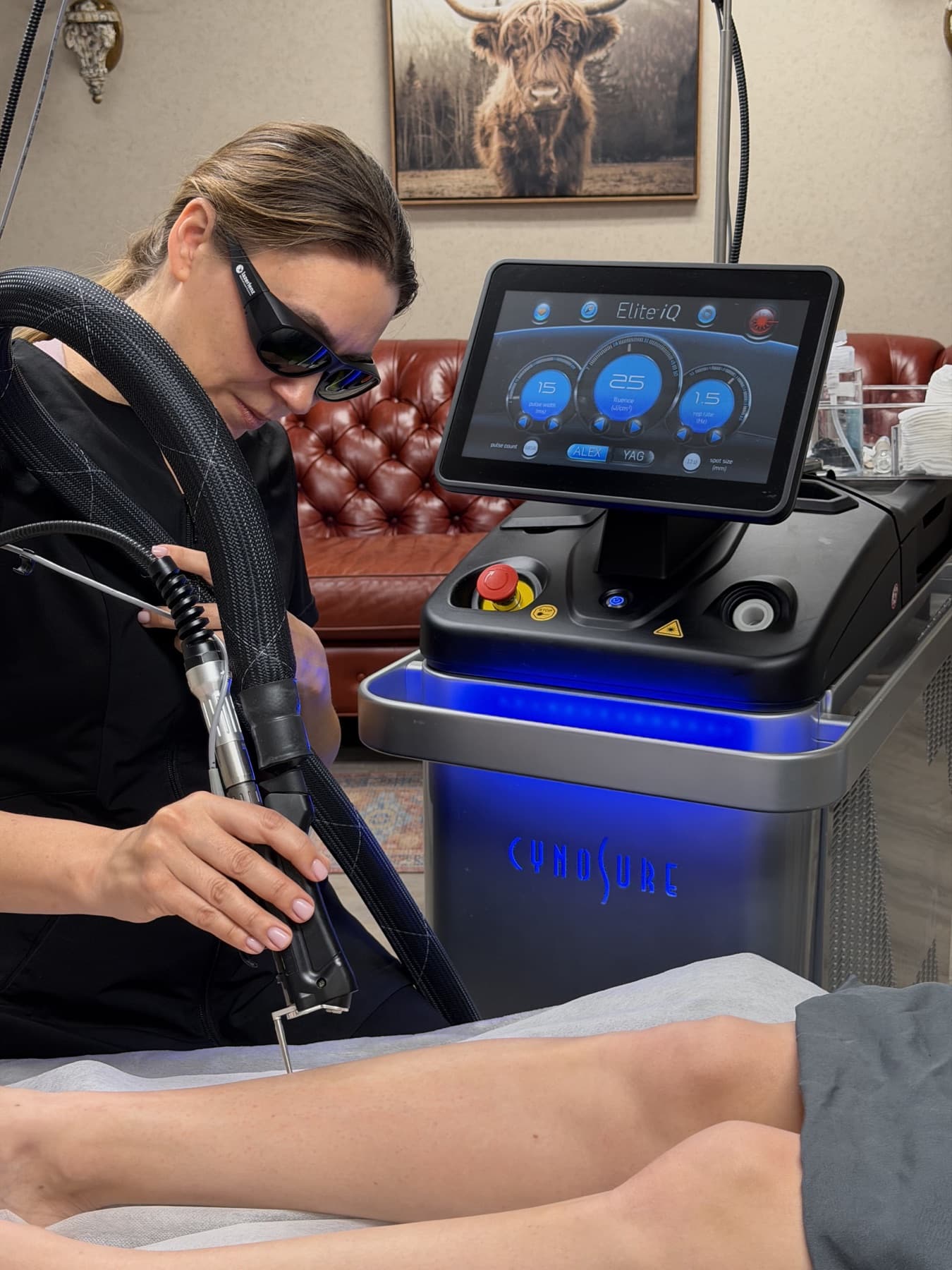 Certified laser technician in protective goggles treating the legs with the Cynosure Elite iQ during a laser hair removal session at LNO Boutique in Centennial, Denver
