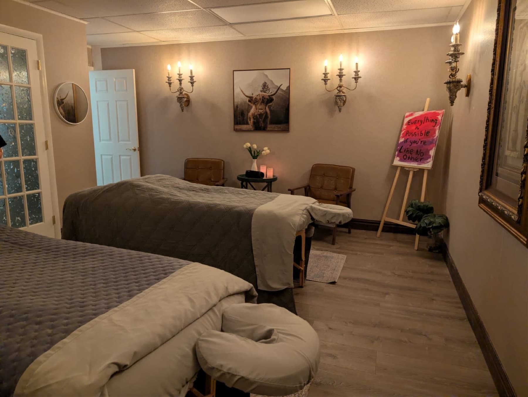 Private couples' massage suite with two tables beneath candle sconces at LNO Boutique in Centennial