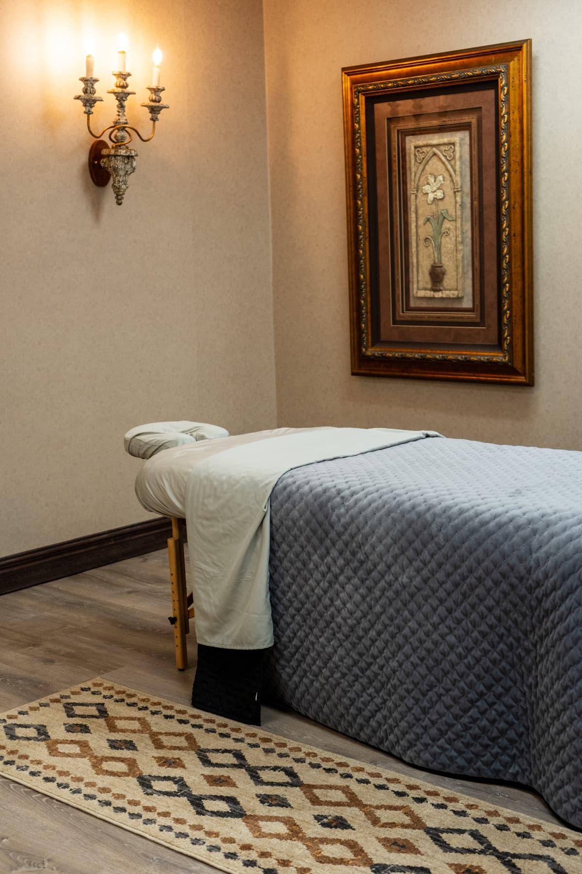 Massage treatment room with a candle sconce and dressed table at LNO Boutique day spa in Centennial, Colorado