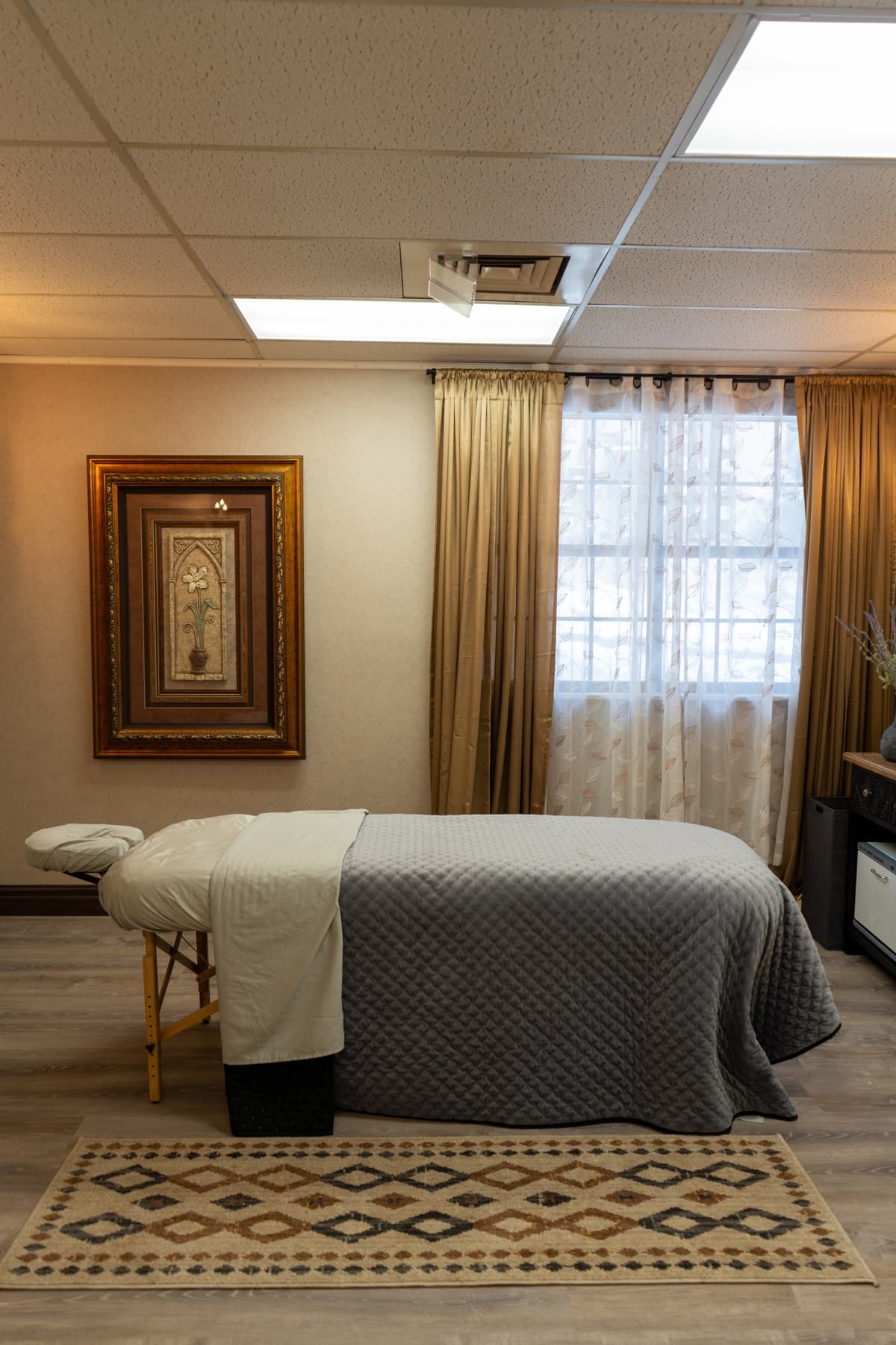 Massage treatment room with a dressed table and soft window light at LNO Boutique, Centennial